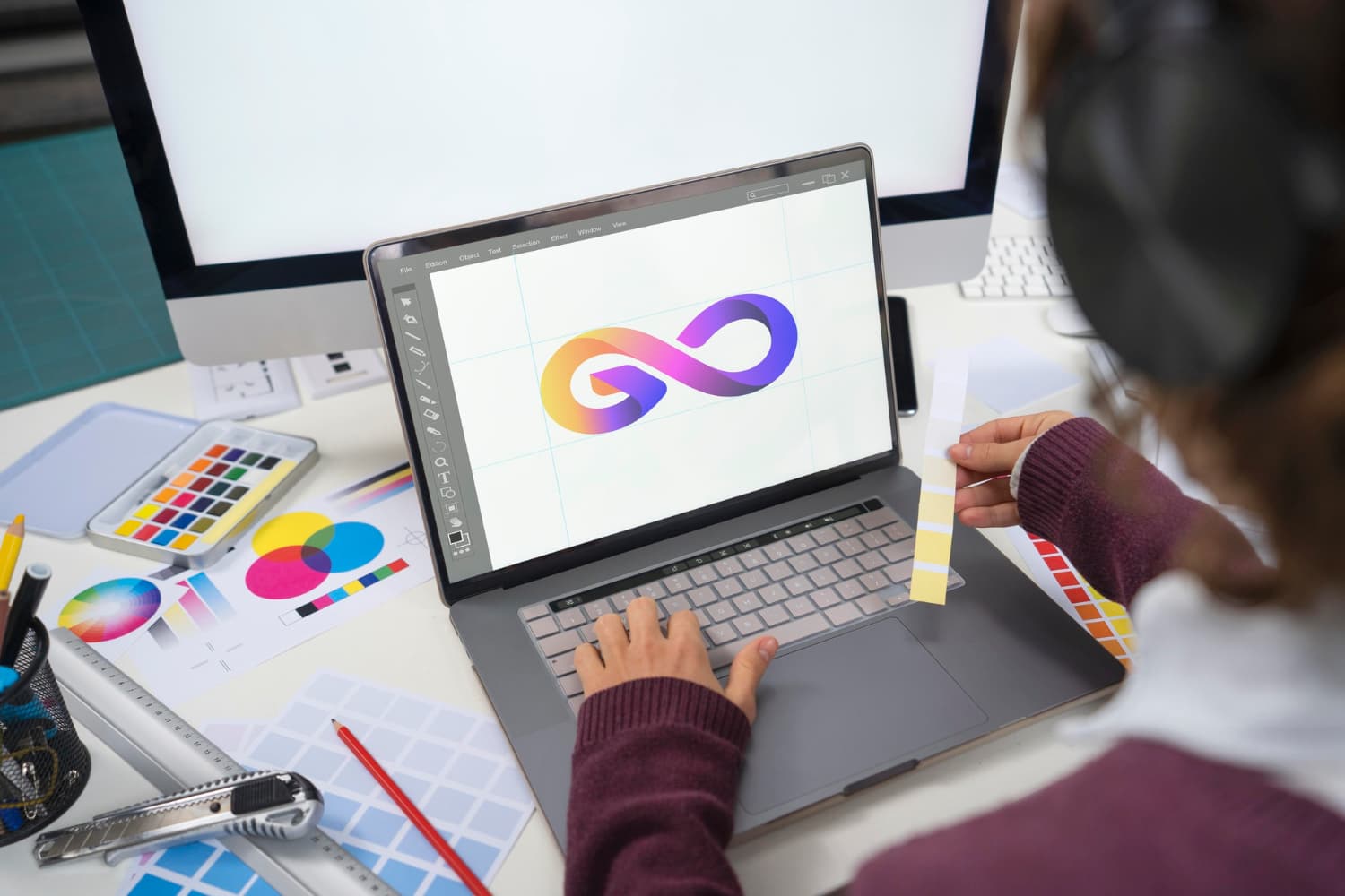 Graphic designer creating a colorful logo on a laptop